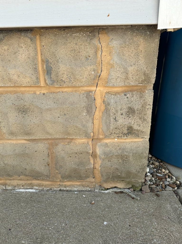Exterior foundation wall with visible structural cracks in residential concrete